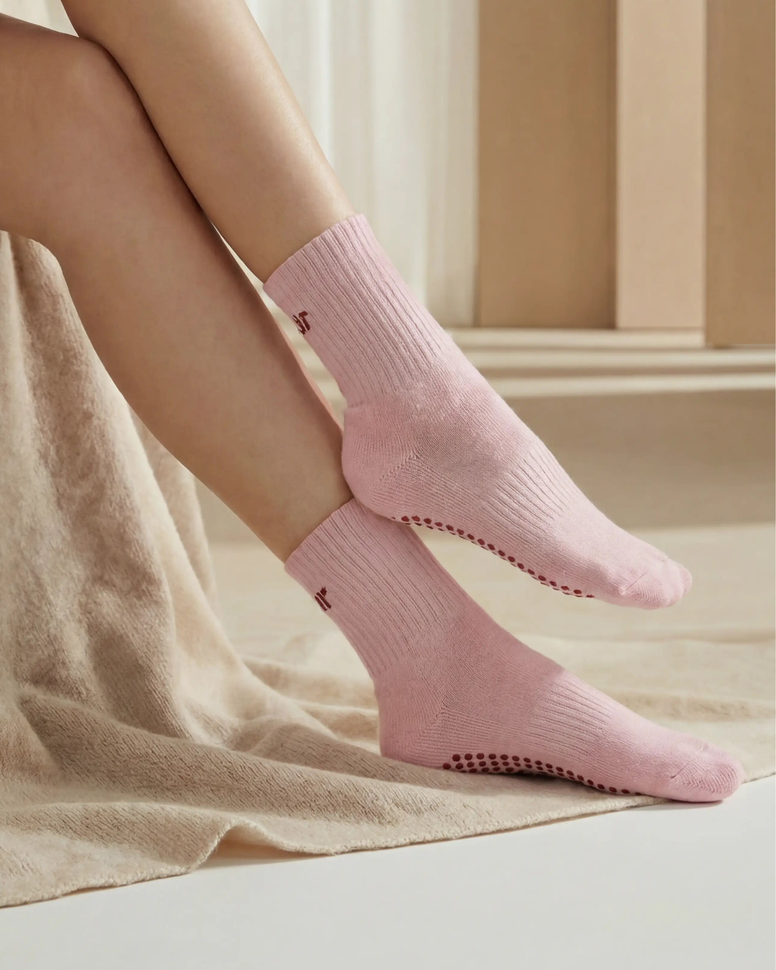 Person wearing pink socks sitting on a beige surface with a neutral-colored wall in the background